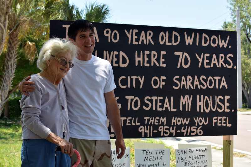 Marie and Miles standing in front of the sign. Image via HeraldTribune.