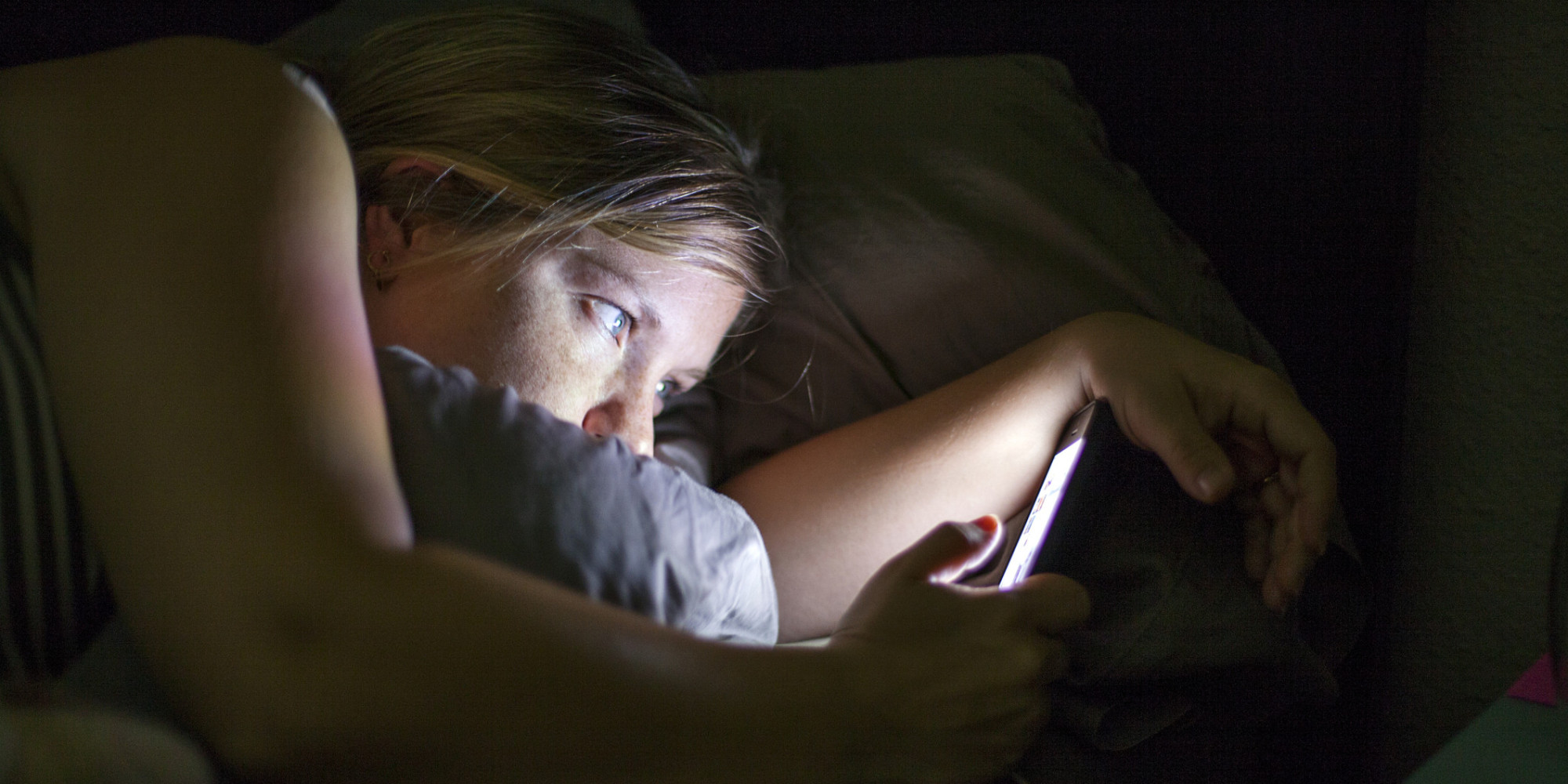 Caucasian woman using cell phone in bed