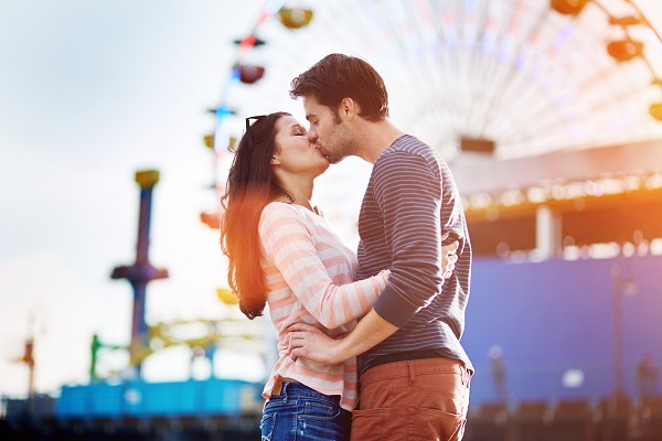 romantic couple kissing in front of santa monica ferris wheel