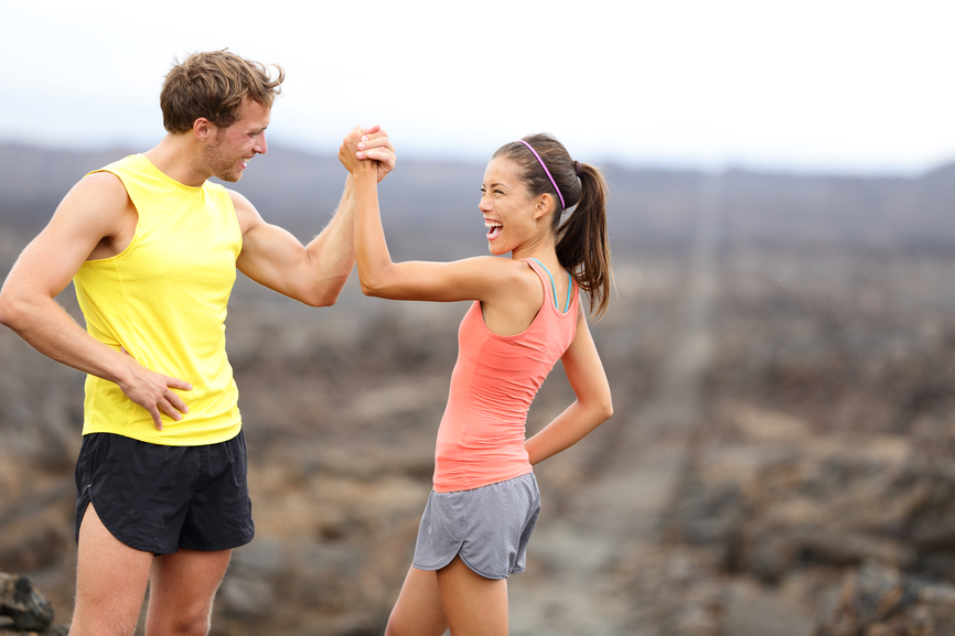 Fitness sport running couple celebrating cheerful and happy giving high five energetic and cheering. Runner couple having fun after trail cross-country running training. Asian woman, Caucasian man.