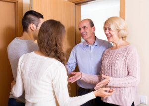 meeting-door-positive-young-couple-inviting-elderly-parents-to-come-inside-49360589