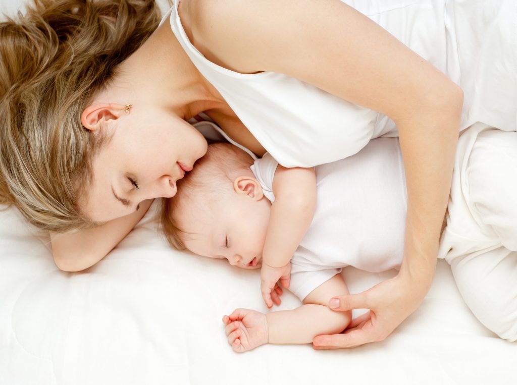 Young mother and her baby, sleeping in bed