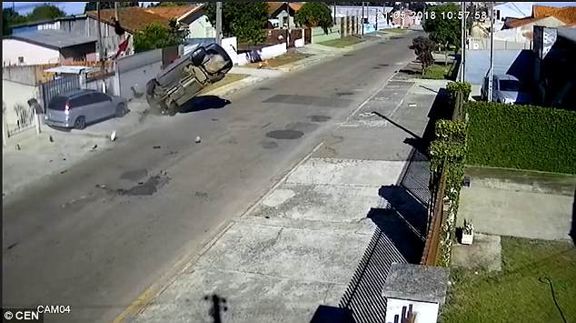 The car rolls and the passenger is thrown from the vehicle into the air before landing on the other side of a high fence