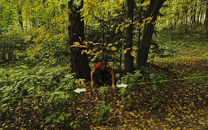 A man crouched by the side of the road wearing a gas mask seen on Google Maps.