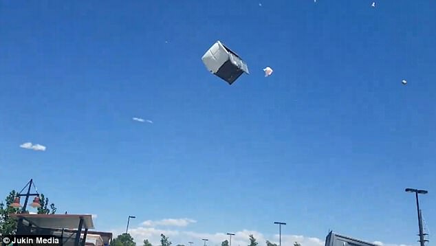 Liquid from the Porta Potty spilled out of the cabin as the portable plastic toilets swirled in the air. A man sheltering a child beneath his arms runs in front of the camera seeking shelter