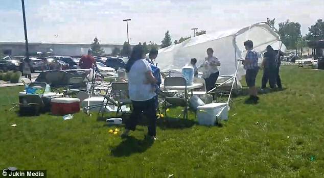 Dozens rush for cover as debris and loose objects are sent hurling through the air, and a mother is seen sheltering her child on all fours