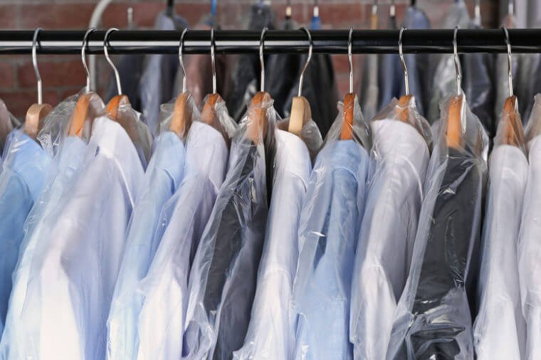Rack of clean clothes hanging on hangers at dry-cleaning
