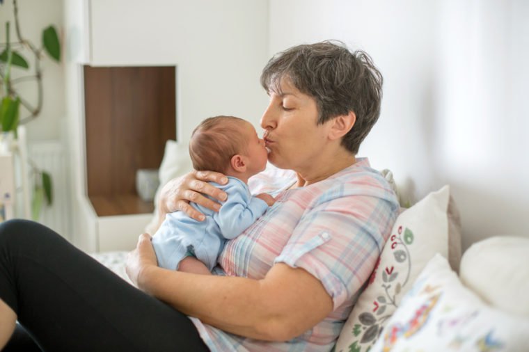Beautiful baby boy in grandmothers arms at home