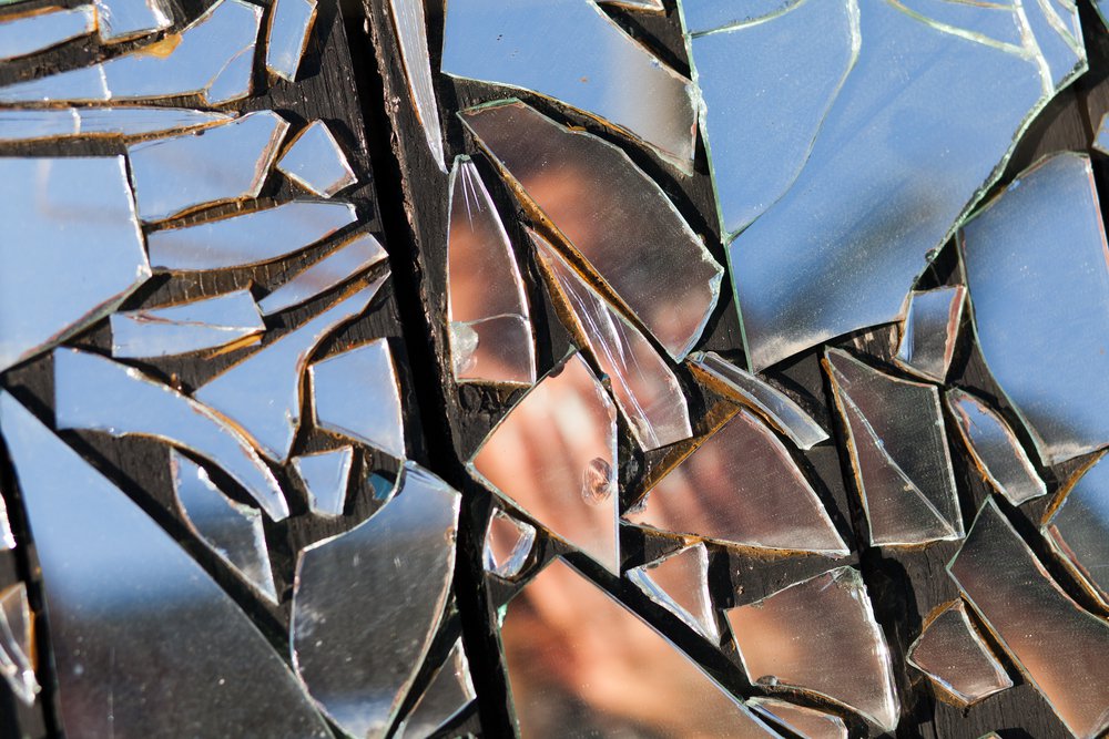 obscured image of a woman in broken glass reflection