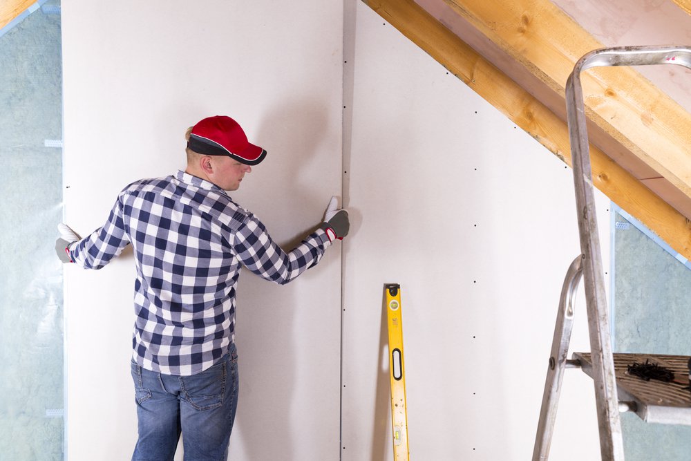 Construction worker holding gypsum board. Attic renovation. Installation of drywall