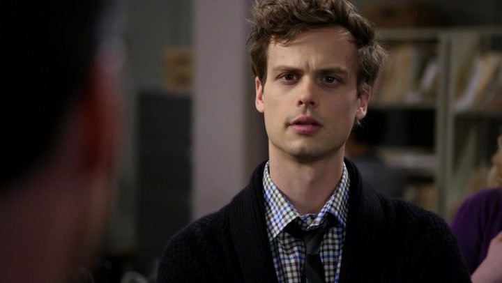Spencer Reid sorprendido dentro de una oficina charlando con otra persona, escena de la serie Mentes Criminales