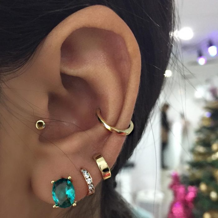 oreja de mujer con pearcings y aretes 