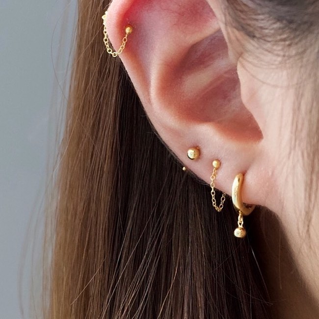 oreja de mujer con pearcings y aretes 