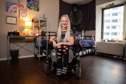 Alex in her bedroom, sitting on her wheelchair 