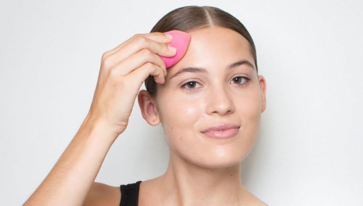mujer con esponja de maquillaje