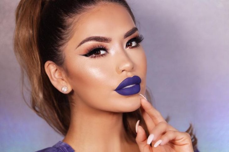 Chica usando un labial color morado mate con iluminador