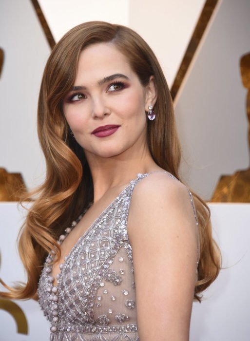 Zoey Deutch usando un vestido gris durante la alfombra roja de los premios Oscar