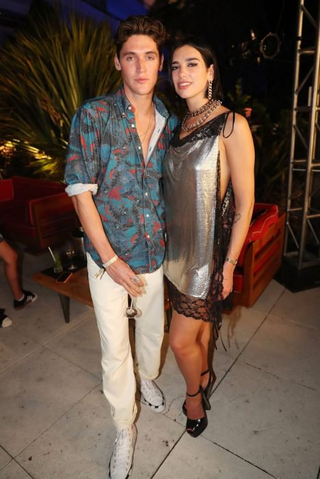 Dua Lipa e Isaac Carew abrazados posando para una foto durante una fiesta