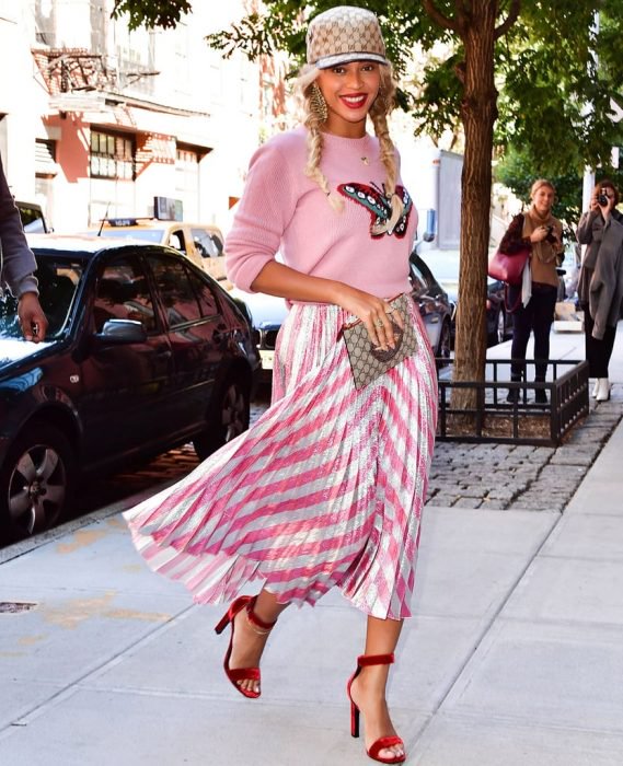 Beyoncé sonriendo y modelando un outfit en color rosa