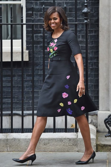 Michelle Obama sonriendo y caminando por la avenida