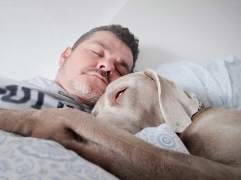 man laying on bed beside dog