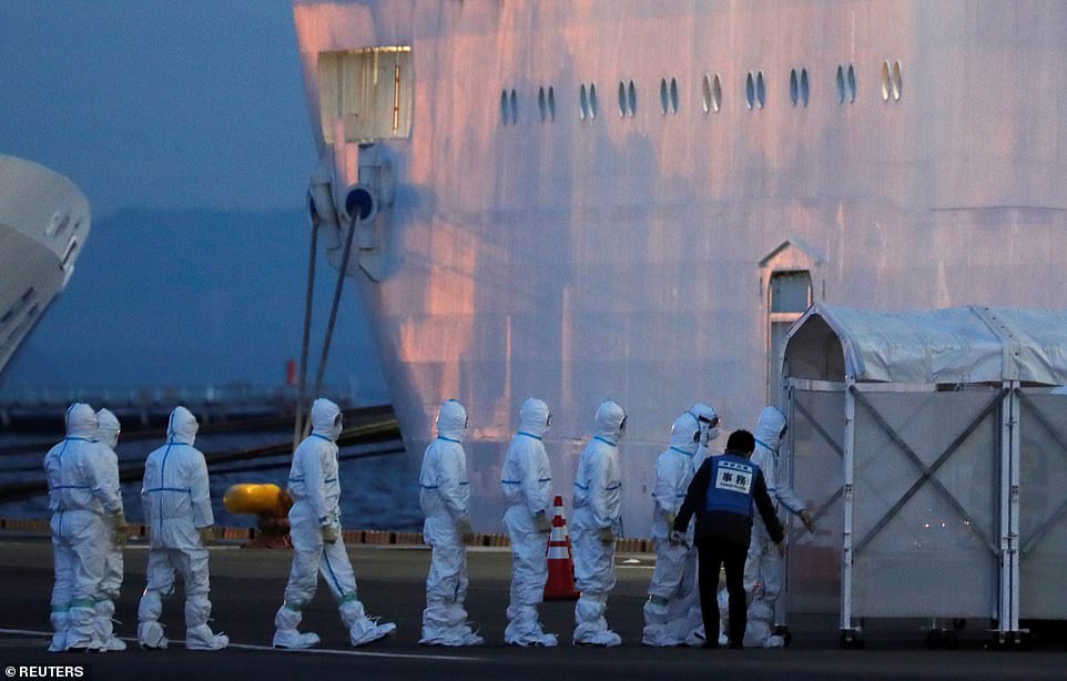 Health workers in protective gear were still working in Yokohama Bay as darkness fell on Friday with the Diamond Princess in quarantine