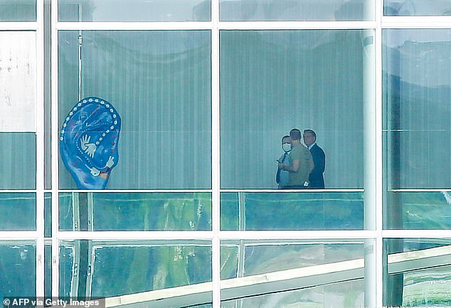 Brazilian President Jair Bolsonaro is pictured with his son Eduardo Bolsonaro (center) and an adviser, inside Alvorada Palace in Brasilia