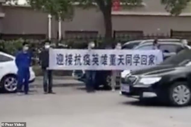 People are seen holding a banner that reads 