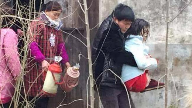 Rescue mission ... villagers carry Zhang Qi from the house where she was allegedly held captive by her parents. Picture: Australscope