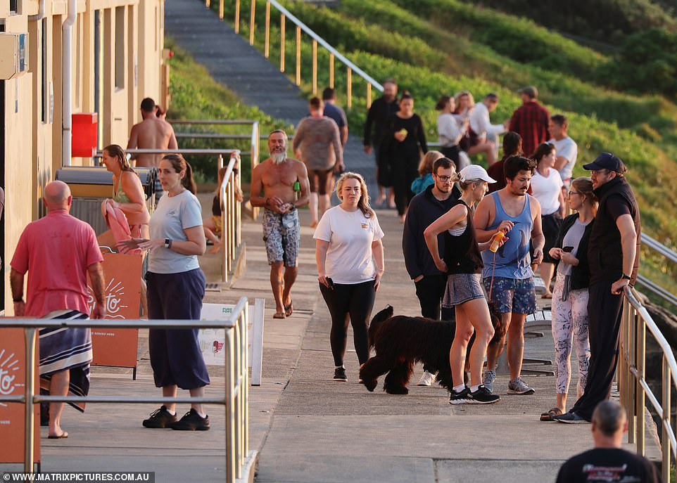 Walkers stand outside a cafe - which is only allowed to serve takeaway food and drinks - on the Northern Beaches on Friday