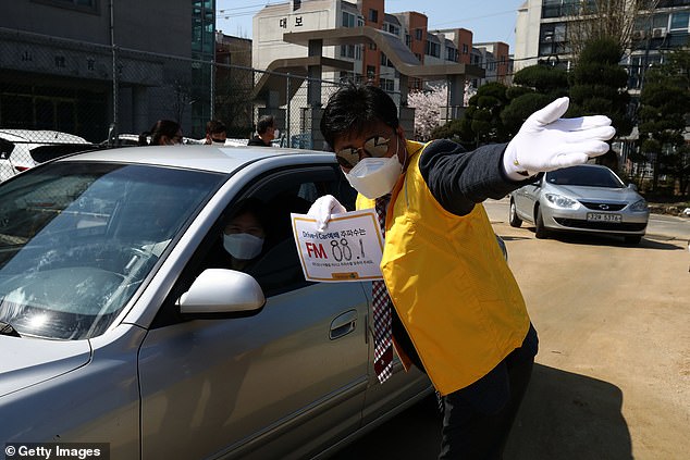 Fifty-one people who recovered from coronavirus in South Korea have tested positive again – raising fears the virus can be reactivated. Pictured: A church worker directs people to a drive-through worship in Seoul