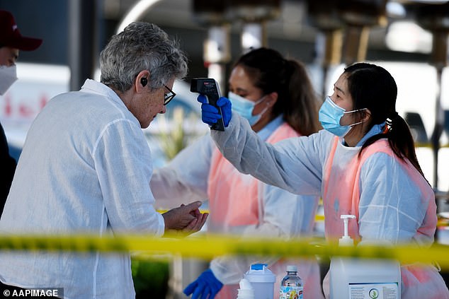 Pictured: A woman has her temperature checked before entering the Sydney Fish Market