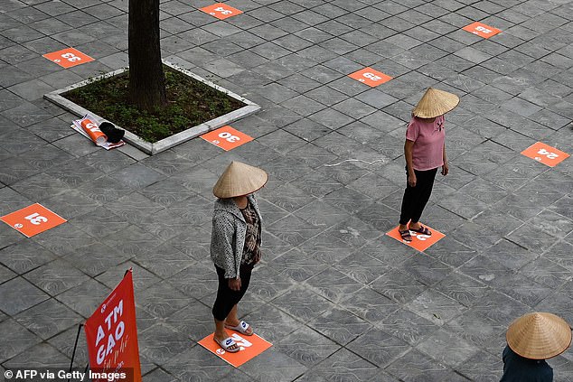 In this file photo taken on April 11, 2020, residents wearing face masks practice social distancing as they wait in a queue for free rice, amid Vietnam