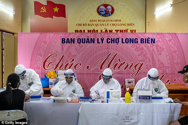 Medical specialists in protective suits collect blood samples from vendors and labourers at Long Bien market as part of their rapid testing program last week in Hanoi, Vietnam