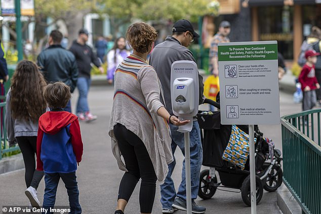 A guest seen with a family reaching for hand sanitizer in the Downtown Disney District shopping mall