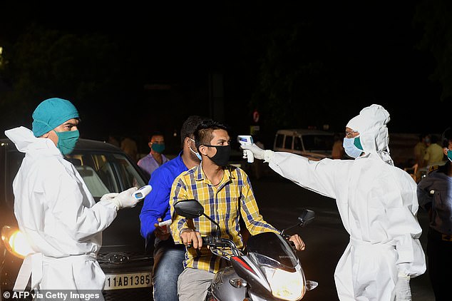 It is unclear from reports which of the two tests was shown to have such a low accuracy rate. Pictured: A health worker checks the body temperature of the rider of a moped in India