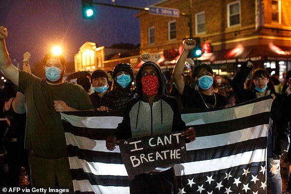People hold up their fists after protesting near the spot where George Floyd died while in custody of the Minneapolis Police, on May 26 in Minneapolis, Minnesota