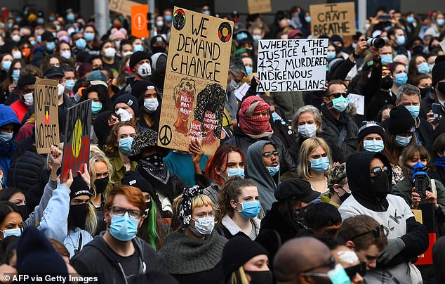 People hold up placards at a Black Lives Matter protest to express solidarity with US protesters in Melbourne on June 6