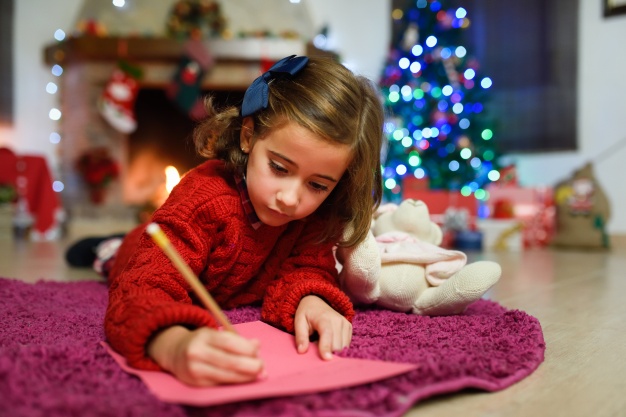 Niña pequeña escribiendo su carta a papa noel | Foto Gratis