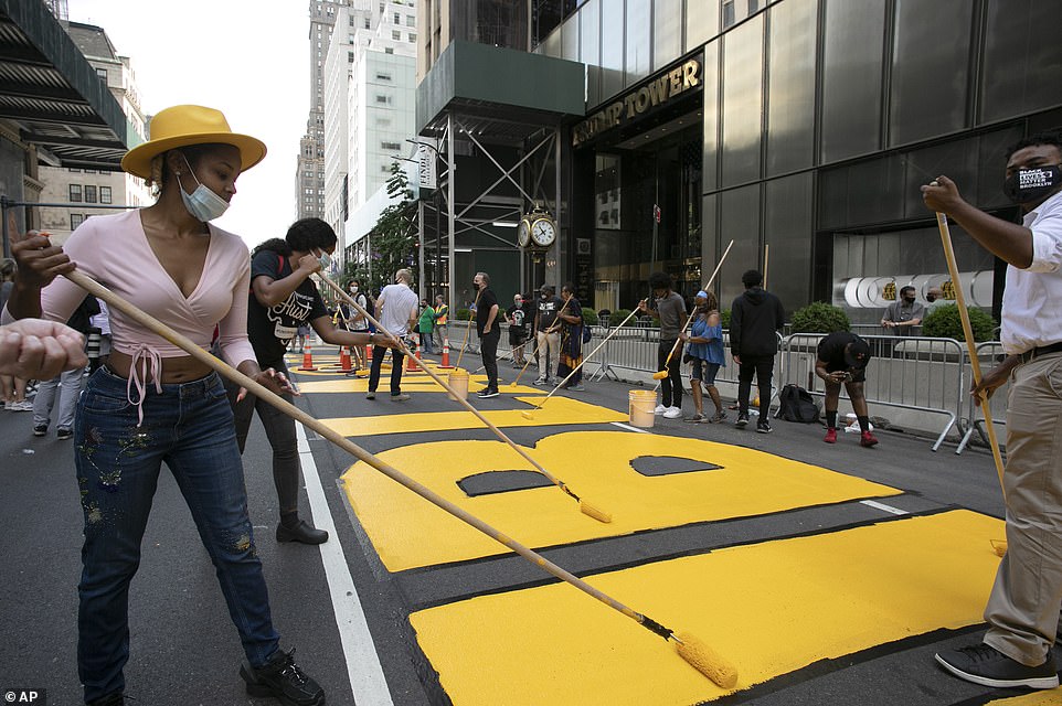 Azia Toussaint, left, participates in the painting of Black Lives Matter on Fifth Avenue in front of Trump Tower, Thursday