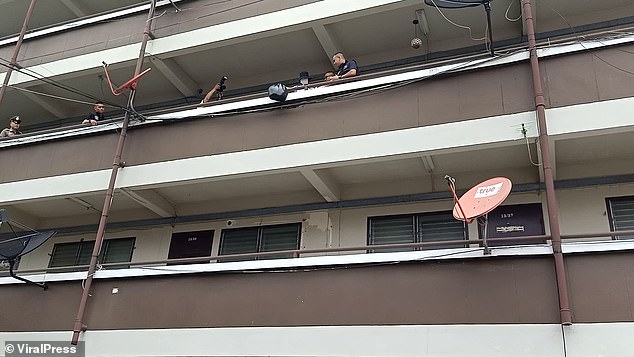 Police later took Aom, pictured holding a black bag, to the flat to recreate the crime