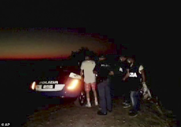 Four people have been arrested in connection with the alleged gang rape. Above, police officers are pictured taking a youth in custody