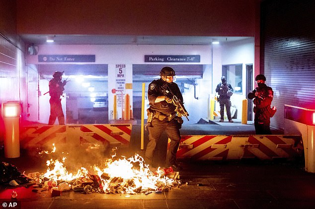 A Department of Homeland Security officer emerges from the Mark O. Hatfield United States Courthouse after demonstrators lit a fire in Portland back on August 2