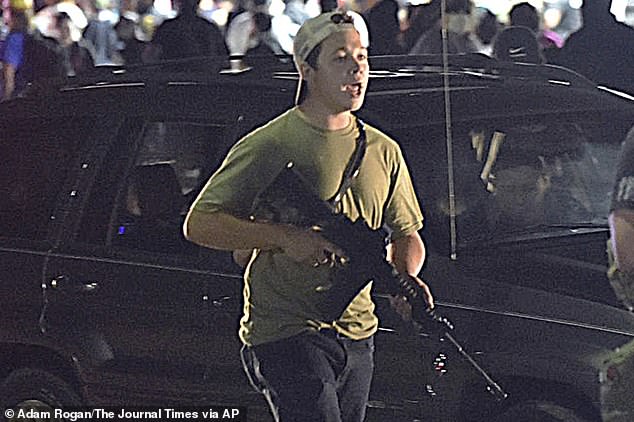 In this August 25 photo, Rittenhouse carries a weapon as he walks along Sheridan Road in Kenosha, Wisconsin, during a night of unrest