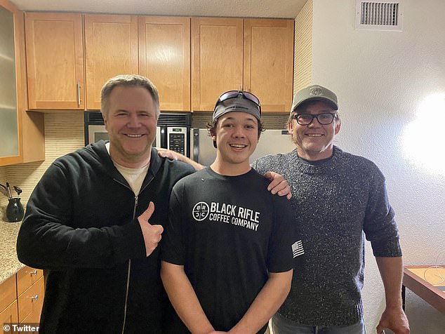 Rittenhouse, center, smiles alongside attorney John Pierce (left) and actor Ricky Schroeder (right)