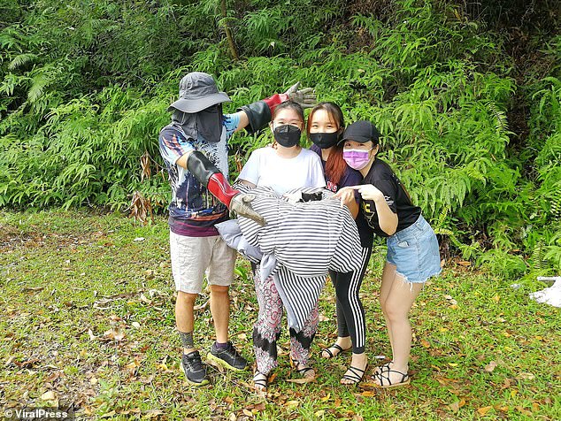 Pictured: The proud locals hold the little puppy in a blanket after their successful rescue mission