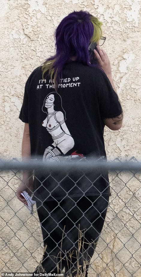 The 24-year-old was seen wearing all black with a T-shirt picturing a naked woman in fishnet tights and red high heels tied up emblazoned with: 