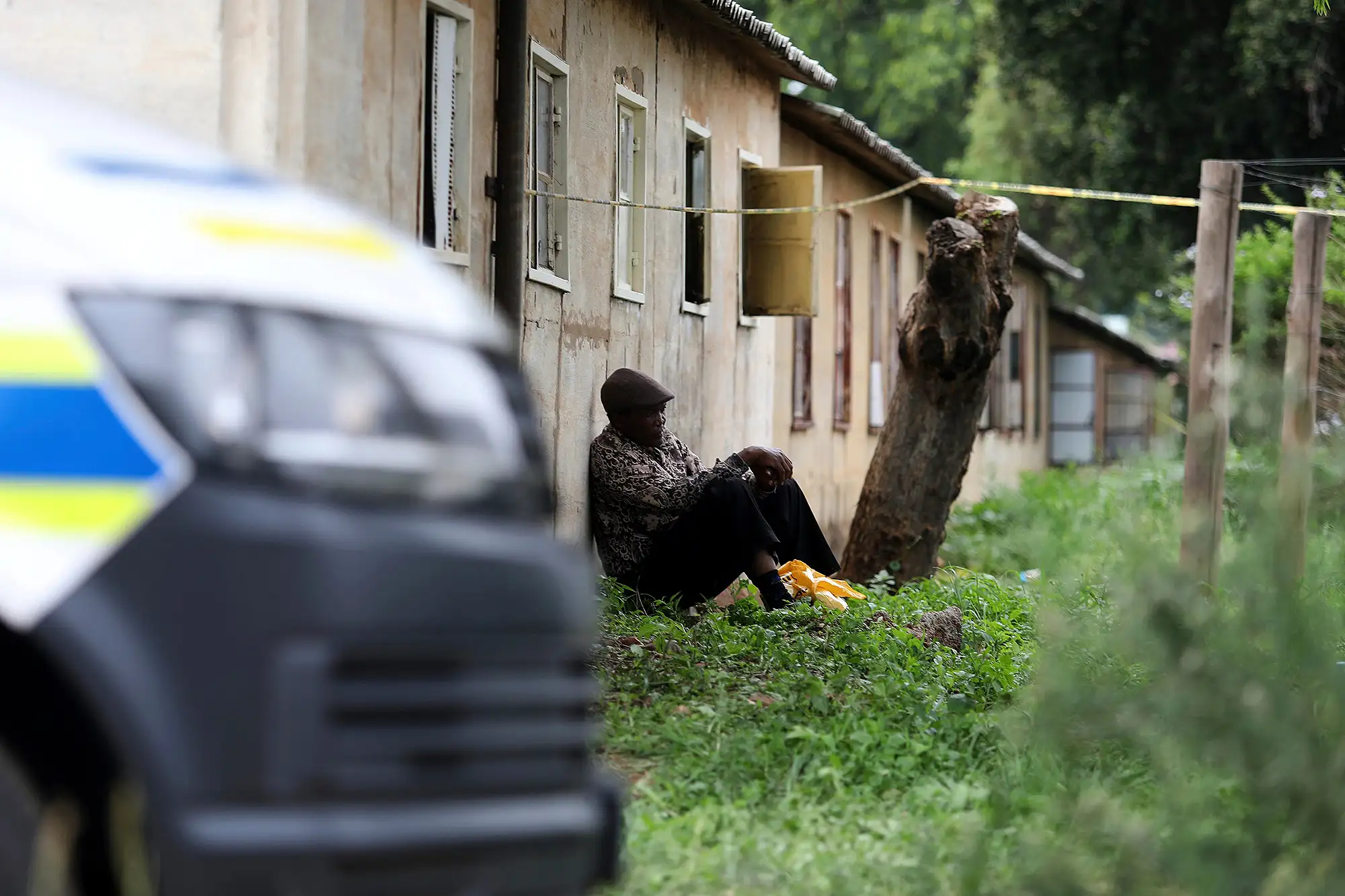 A man sits outside a scene where the bodies of the victims of a mass shooting were found, at a bar near Pretoria, South Africa, Saturday, Dec. 6, 2025.
